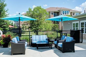 a patio with chairs and umbrellas in front of a house